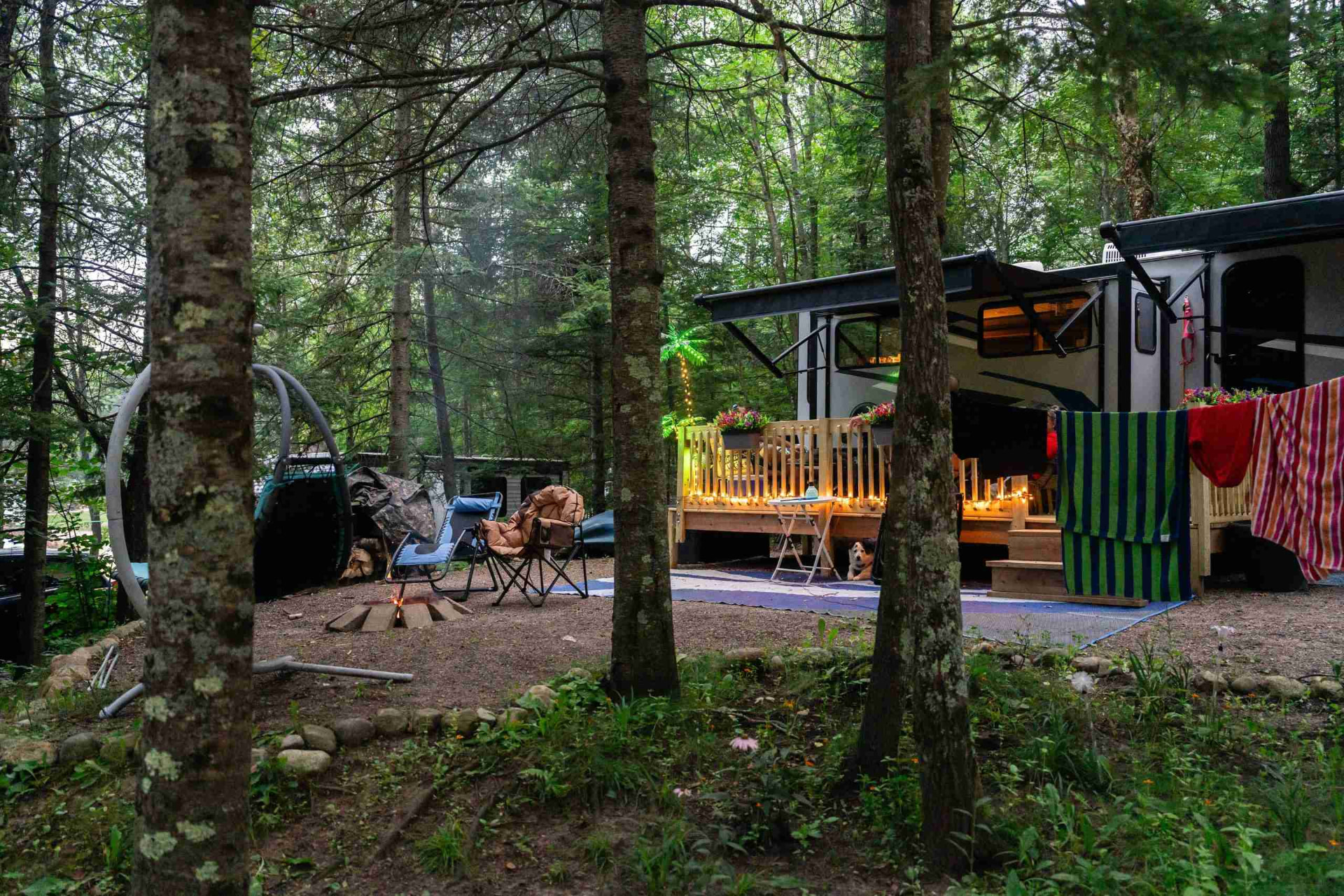 A monthly RV site with a wooden deck and campfire at Heaven’s Up North Campground
