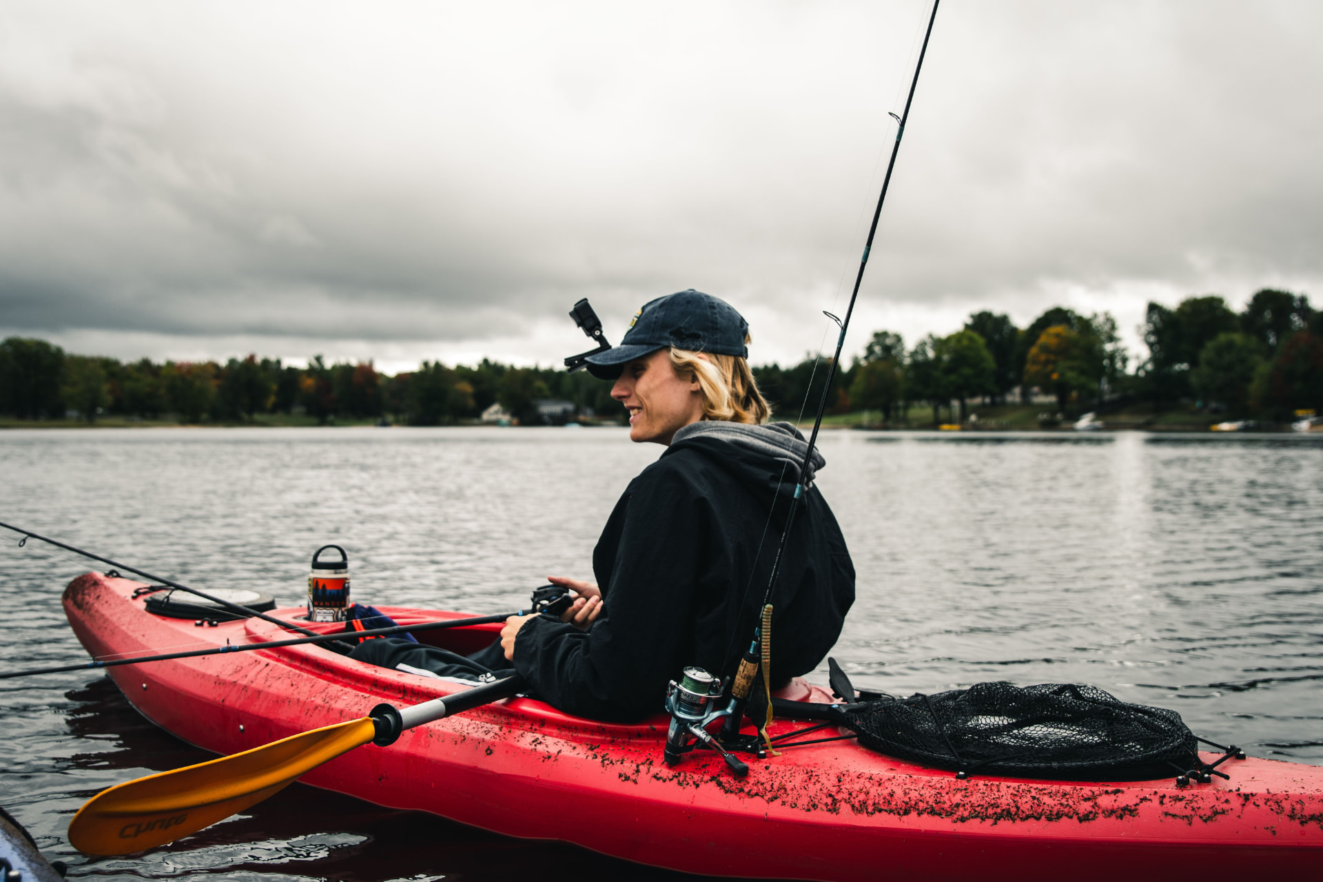 An angler fishing from a red kayak on a Northwoods lake
