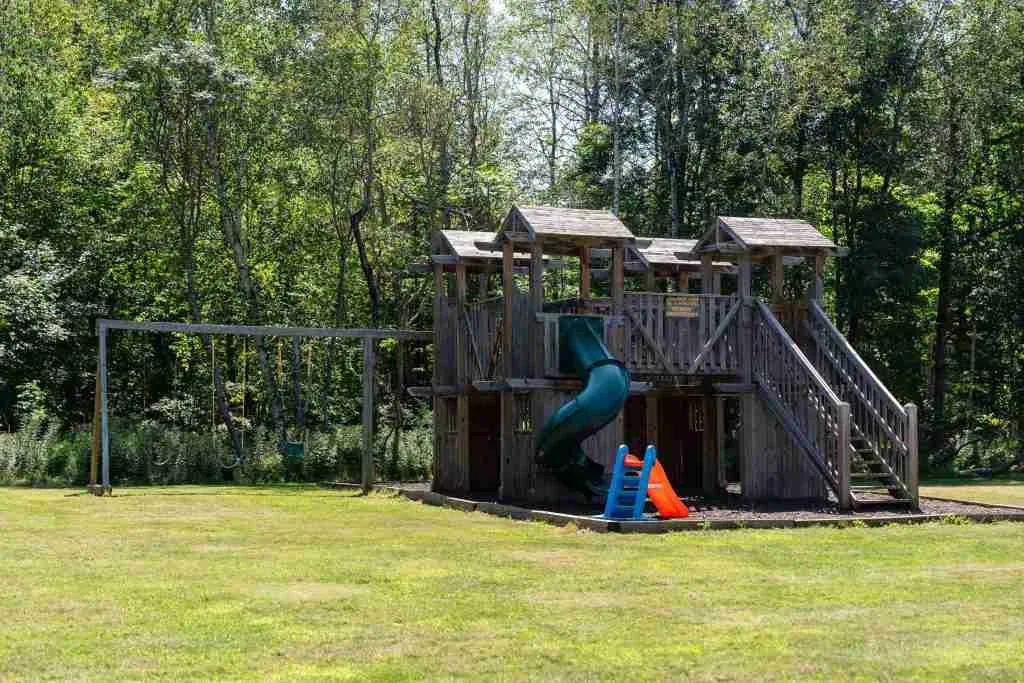 Wooden playground structure on a grassy campground lawn